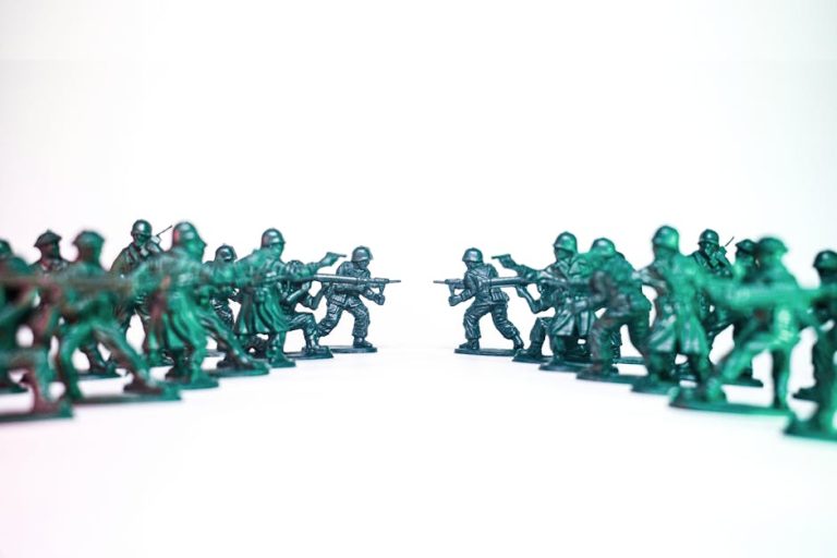 Green toy soldiers facing off on a white background, symbolic of conflict and strategy.