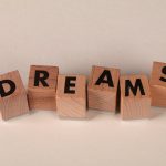 The Strategic Utility of Dreams in High-Performance Leadership Wooden blocks arranged to spell 'DREAMS' against a soft neutral backdrop, symbolizing ambition.
