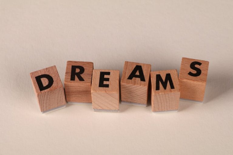 Wooden blocks arranged to spell 'DREAMS' against a soft neutral backdrop, symbolizing ambition.