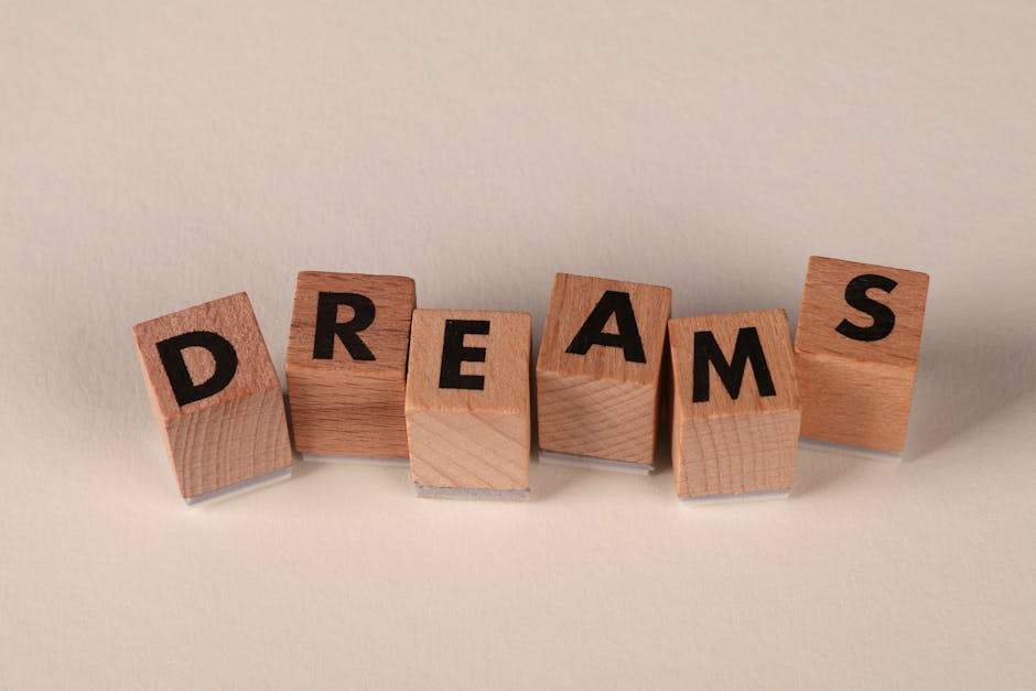Wooden blocks arranged to spell 'DREAMS' against a soft neutral backdrop, symbolizing ambition.