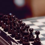 The Strategic Utility of Storytelling in Literature and Business Close-up of black chess pieces aligned on a chessboard, ready for play.