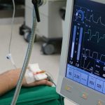 The Trauma of Technology: How Digital Architecture Shapes Human Behavior A close-up of a patient's hand connected to medical equipment in an ICU room.