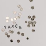 A visually striking flatlay of coins with 'Taxes' text on a white surface, ideal for financial concepts.