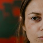 The Trauma Tax: How Unresolved Experiences Sabotage Strategic Execution Close-up portrait of a woman with a bruised eye, depicting emotion and resilience.