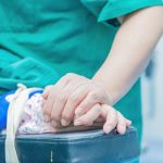 Medical professional comforting a patient by holding hands in an operating room setting.