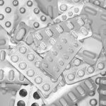 Monochrome close-up of assorted blister packs with pills, highlighting pharmaceutical packaging.