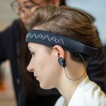 Close-up of a young woman wearing an EEG headband, showcasing modern technology indoors.