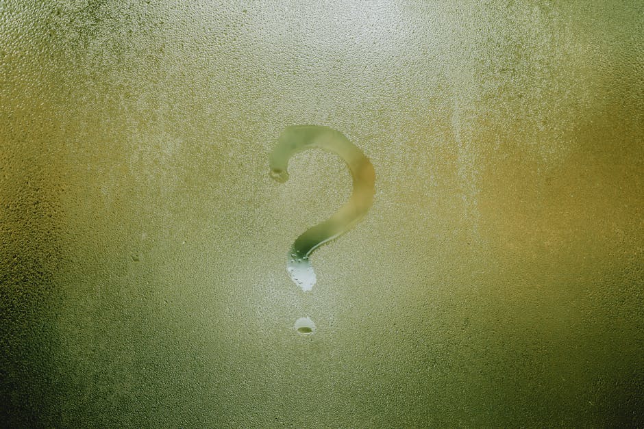 Translucent wet glass window covered with water drops with question mark on surface