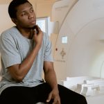 A man sits nervously in an MRI scan room, contemplating his health diagnosis.