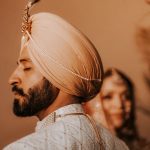 A striking portrait of a Sikh groom in traditional clothing, featuring a turban and beard.