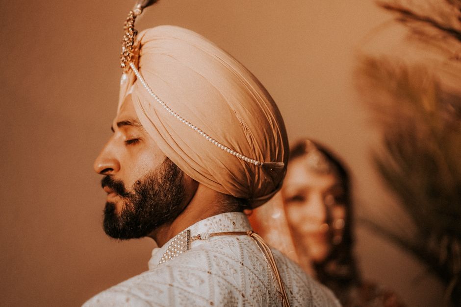 A striking portrait of a Sikh groom in traditional clothing, featuring a turban and beard.