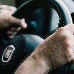 Hands firmly gripping a car steering wheel, ready to drive.