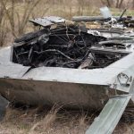 Close-up of a destroyed military tank in an outdoor setting, emphasizing war's impact.