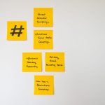 Why Creative Strategy Is the New Engine of Technical Execution Organized yellow sticky notes on a white wall for holiday marketing strategies.