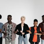 Five diverse adults standing together, linking arms, symbolizing unity and solidarity on a white background.