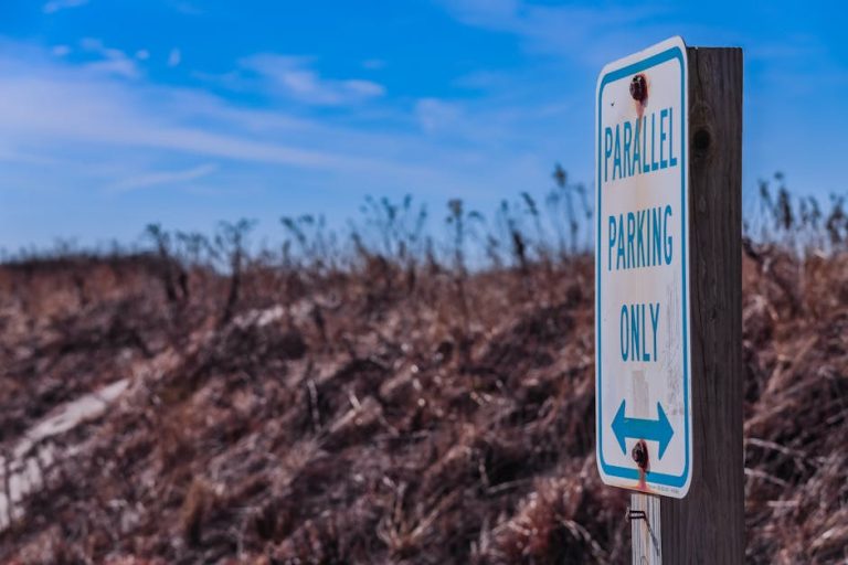 An outdoor parking sign emphasizing parallel parking only, set against a rustic autumn field.