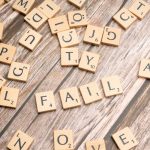 Scrabble tiles on wood form 'FAIL', symbolizing defeat and reflection.