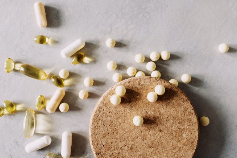 A mix of various capsules and pills scattered on a cork surface, depicting healthcare and wellness.