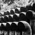 Why Urban Design Is the Silent Architect of Educational Performance Snow-covered industrial pipes with graffiti, set in a forested area, depicted in black and white.
