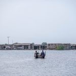 People wading through floodwaters in Gandakha City, highlighting the impact of the 2022 floods in Balochistan, Pakistan.