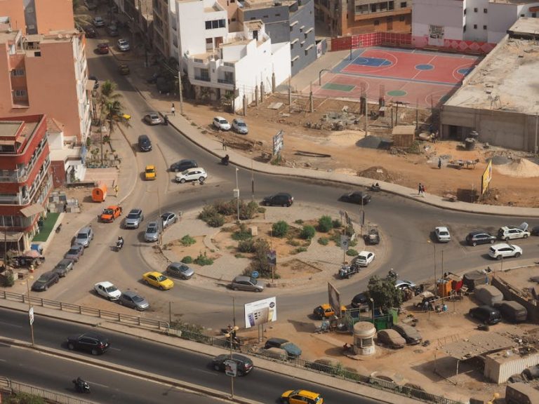 High-angle shot of a busy urban roundabout with vehicles and surrounding buildings.