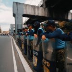 Row of police officers in uniform guarding a street during a demonstration.