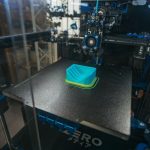 Additive Manufacturing: Strategy for Operational Excellence Close-up of a 3D printer creating a plastic object in an industrial setting.