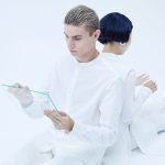 Aesthetic Theory: The Future of Business Strategy & Value Two adults interacting with transparent tablets, showcasing modern technology in a futuristic white setting.