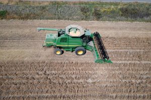 Aerial shot of combine harvester operating in an agricultural field during harvest season.