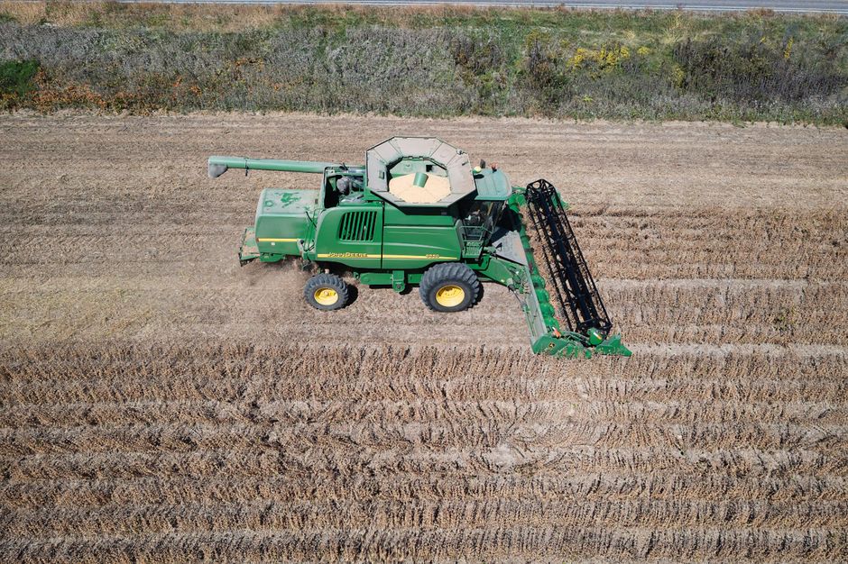Aerial shot of combine harvester operating in an agricultural field during harvest season.