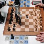 AI Augmentation vs Replacement: A Strategic Business Guide A robotic arm playing chess against a human hand on an electronic chessboard indoors.