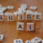 Scrabble letters spelling 'GUIDE' and 'AI' on a wooden surface, suggesting direction and technology.