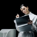 A female scientist with futuristic attire reviews notes in an advanced lab setting.
