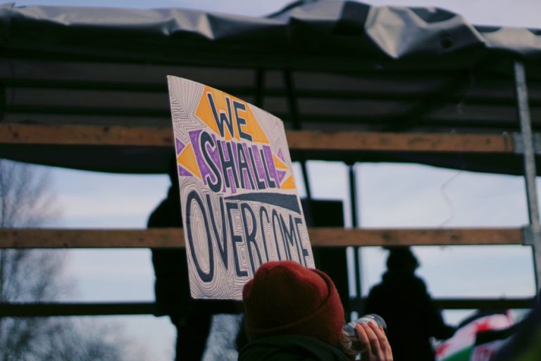 Protesters holding a 'We Shall Overcome' sign during a rally in Berlin, Germany.