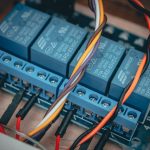 Blue relay modules with colorful wires connected on an electronic board.