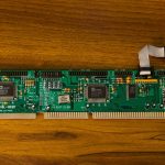 Close-up of a vintage computer circuit board showcasing intricate electronic details on a wooden surface.