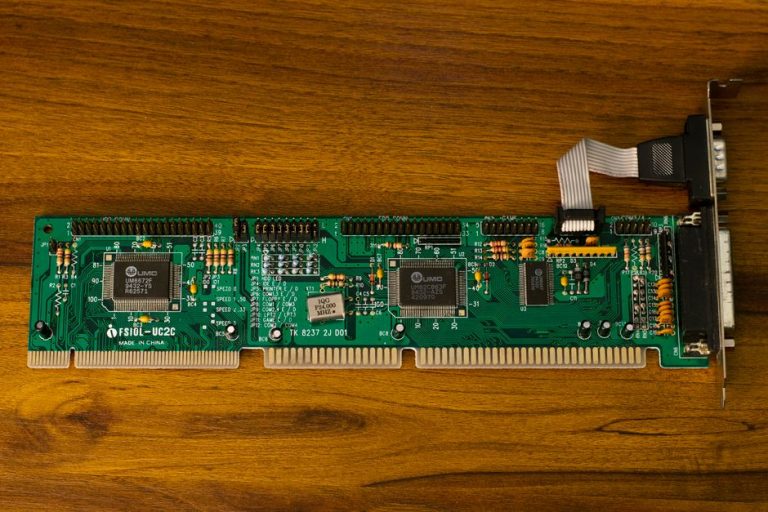 Close-up of a vintage computer circuit board showcasing intricate electronic details on a wooden surface.