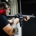 AR in Professional Training: Transforming Spatial Learning Man with earmuffs aiming a rifle at an indoor shooting range.