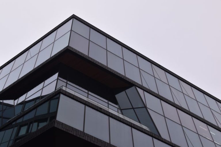 A striking modern building in Amsterdam with a reflective glass facade showcasing sleek architectural design.
