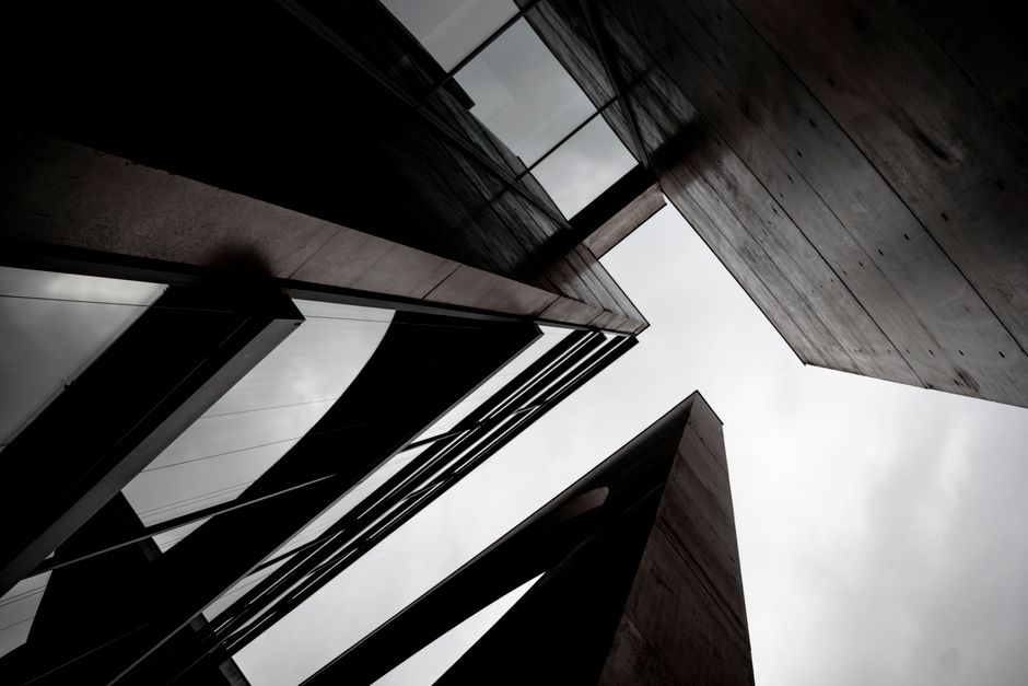 Intriguing angle of contemporary skyscrapers with glass and concrete elements against cloudy sky.
