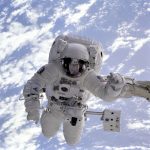 Artificial Gravity: Using Strategic Constraints for Performance Astronaut conducting a spacewalk with Earth in the background, showcasing outer space exploration.