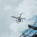 A drone hovering in the sky amidst clouds, showcasing technology in action.