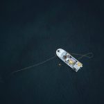 Autonomous Deep-Sea Mapping: Closing the Data Strategy Gap Aerial photograph of a single boat anchored in a vast, dark ocean, captured from above.