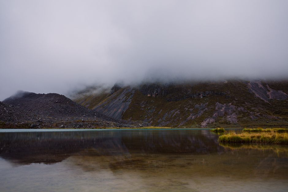 Serene lake with misty mountains in Pajchanta, Peru, reflecting natural beauty.