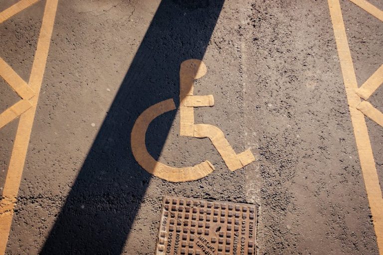 Close-up of a yellow wheelchair symbol painted on asphalt, highlighting accessibility.