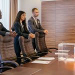 Beyond the Ballot: Why Corporate Sovereignty Now Requires a Protocol-First Political Strategy A diverse group of professionals discuss around a ballot box in a conference room.