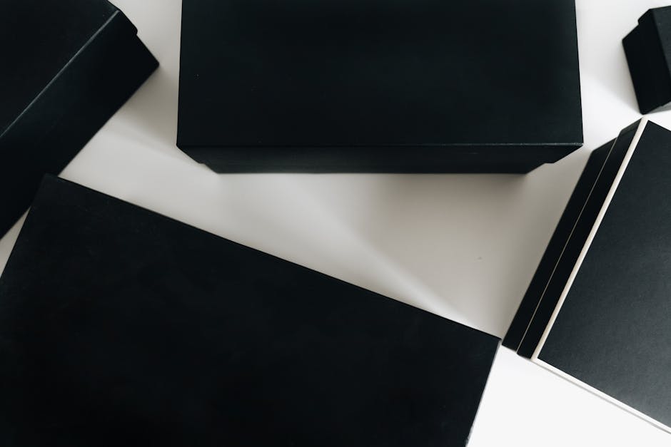 Top view of sleek black boxes arranged artfully on a white surface, showcasing minimalist design.