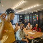 Beyond the Ideation Trap: Why 'Structured Friction' is the Real Driver of High Performance Group of professionals collaborating in an office, brainstorming on glass board.