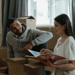 A couple exploring their new home while unpacking boxes and looking at a photo album.