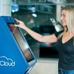 A woman using a Coin Cloud digital currency ATM indoors, highlighting modern technology.